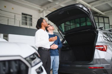 Erkek müşterinin portresi galeride profesyonel araba satıcısıyla konuşuyor. Yeni otomobil seçimi ve satın alma kavramı.