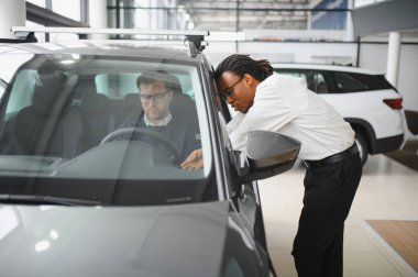 Bir araba galerisinde danışman, müşteriye yeni bir araba seçmesinde yardımcı olur..