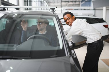 Bir araba galerisinde danışman, müşteriye yeni bir araba seçmesinde yardımcı olur..