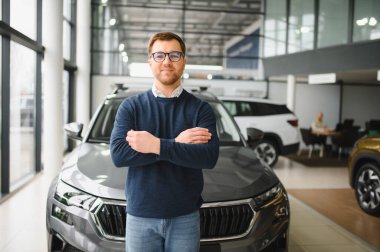 Genç adam yeni bir araç içinde araba Bayilik seçmektir.