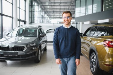 Genç adam yeni bir araç içinde araba Bayilik seçmektir.