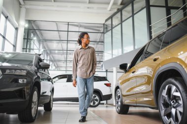 Genç Afrikalı Amerikalı adam araba galerisinde yeni bir araç seçiyor..