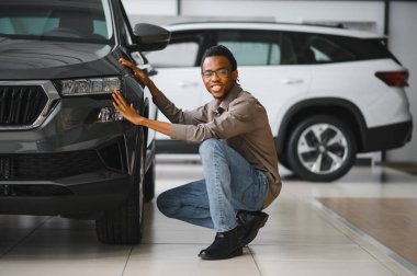 Genç adam yeni bir araç içinde araba Bayilik seçmektir.