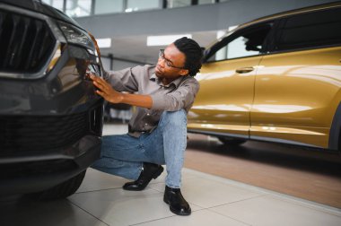 Genç Afrikalı Amerikalı adam araba galerisinde yeni bir araç seçiyor..