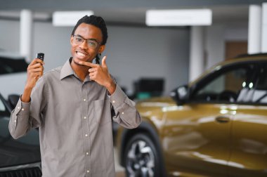 Genç Afrikalı Amerikalı adam araba galerisinde yeni bir araç seçiyor..