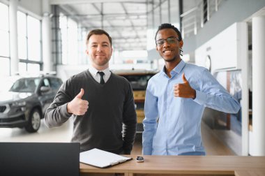 Müşteri erkek, galeride otomobil satın alıyor, araba satıcısıyla kağıt imzalıyor. Galeride yeni otomobil alma kavramı.