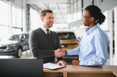 Kafkasyalı satış temsilcisi ve Afrikalı müşteri bayilikte el sıkışırken, satışı kabul ettiler..