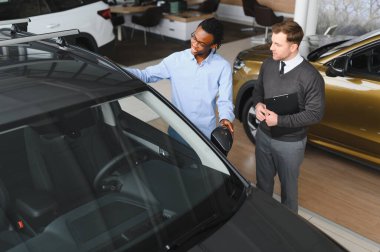 Bir araba galerisinde danışman, müşteriye yeni bir araba seçmesinde yardımcı olur..