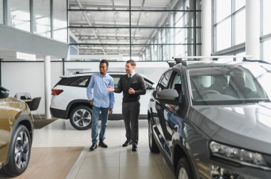 Bir araba galerisinde danışman, müşteriye yeni bir araba seçmesinde yardımcı olur..