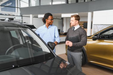 Erkek müşterinin portresi galeride profesyonel araba satıcısıyla konuşuyor. Yeni otomobil seçimi ve satın alma kavramı.