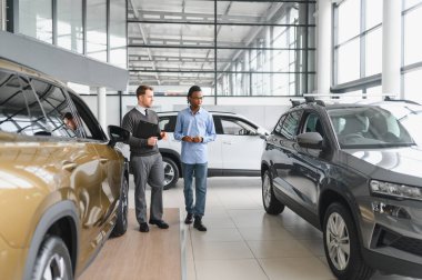 Bir araba galerisinde danışman, müşteriye yeni bir araba seçmesinde yardımcı olur..