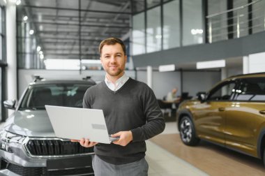 Modern araba satıcısının portresi fotokopi alanı olan bir araba salonunda duruyor..