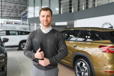 Modern araba satıcısının portresi fotokopi alanı olan bir araba salonunda duruyor..