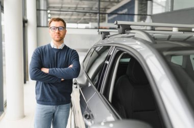 Bugün yeni bir araba aldım. Yerel bayilikte yeni arabasının yanında poz veren mutlu, olgun bir adamın portresi..