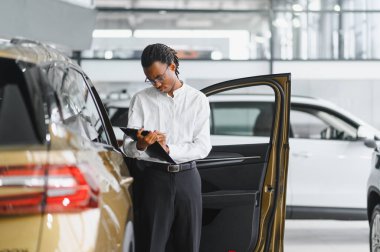 Modern araba satıcısının portresi fotokopi alanı olan bir araba salonunda duruyor..