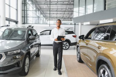 Afrikalı araba satıcısı araba galerisinde duruyor ve müşterilerin satışa çıkmasını bekliyor..