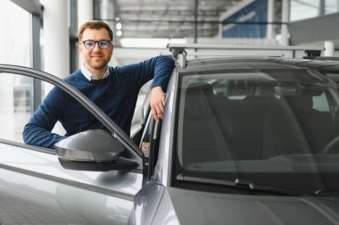 Bugün yeni bir araba aldım. Yerel bayilikte yeni arabasının yanında poz veren mutlu, olgun bir adamın portresi..