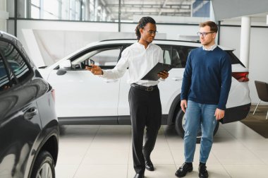 Bir araba galerisinde danışman, müşteriye yeni bir araba seçmesinde yardımcı olur..