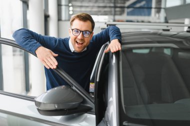 Bugün yeni bir araba aldım. Yerel bayilikte yeni arabasının yanında poz veren mutlu, olgun bir adamın portresi..