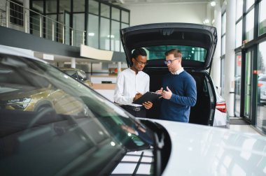 Erkek müşterinin portresi galeride profesyonel araba satıcısıyla konuşuyor. Yeni otomobil seçimi ve satın alma kavramı.