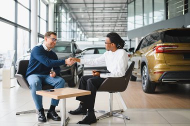 Kafkasyalı satış temsilcisi ve Afrikalı müşteri bayilikte el sıkışırken, satışı kabul ettiler..