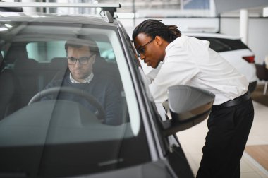 Bir araba galerisinde danışman, müşteriye yeni bir araba seçmesinde yardımcı olur..