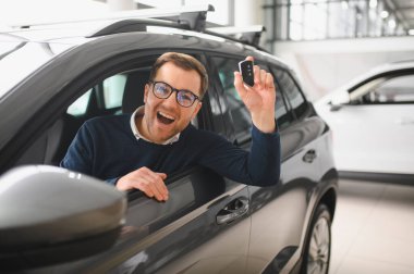 Genç adam yeni bir araç içinde araba Bayilik seçmektir.