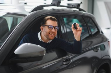 Genç adam yeni bir araç içinde araba Bayilik seçmektir.