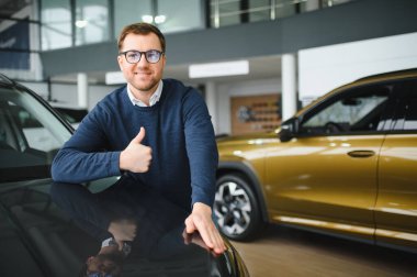 Bugün yeni bir araba aldım. Yerel bayilikte yeni arabasının yanında poz veren mutlu, olgun bir adamın portresi..