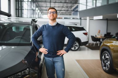 Bugün yeni bir araba aldım. Yerel bayilikte yeni arabasının yanında poz veren mutlu, olgun bir adamın portresi..