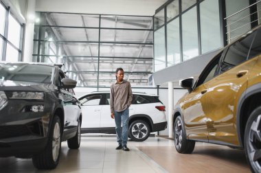 Genç Afrikalı Amerikalı adam araba galerisinde yeni bir araç seçiyor..