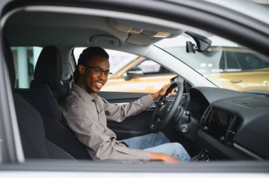 Genç yakışıklı bir adam araba galerisinde araba seçiyor..