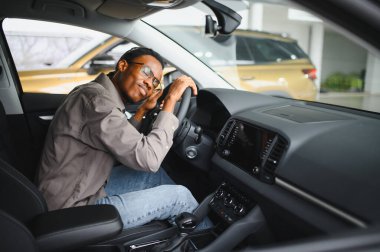 Genç Afrikalı Amerikalı adam araba galerisinde yeni bir araç seçiyor..