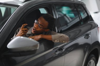 Genç Afrikalı Amerikalı adam araba galerisinde yeni bir araç seçiyor..