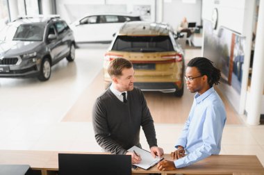 Bir araba galerisinde danışman, müşteriye yeni bir araba seçmesinde yardımcı olur..