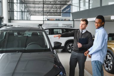 Erkek müşterinin portresi galeride profesyonel araba satıcısıyla konuşuyor. Yeni otomobil seçimi ve satın alma kavramı.