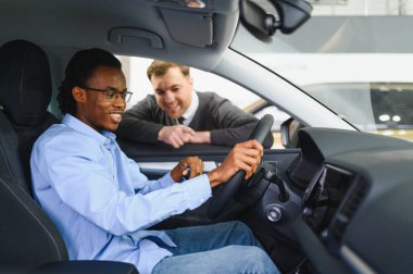 Erkek müşterinin portresi galeride profesyonel araba satıcısıyla konuşuyor. Yeni otomobil seçimi ve satın alma kavramı.