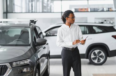 Modern araba satıcısının portresi fotokopi alanı olan bir araba salonunda duruyor..