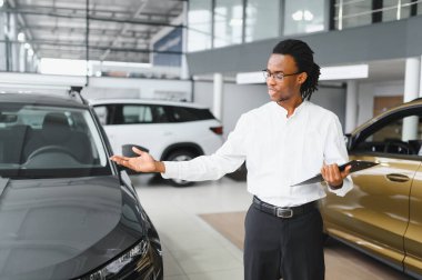 Afro-Amerikan araba satıcısı, galeride duruyor..