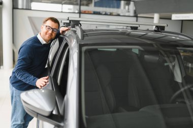 Genç adam yeni bir araç içinde araba Bayilik seçmektir.