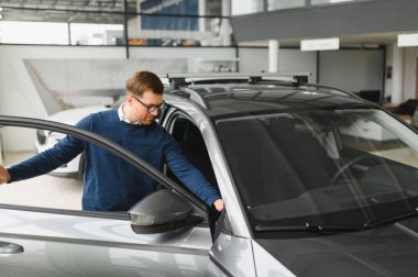 Bugün yeni bir araba aldım. Yerel bayilikte yeni arabasının yanında poz veren mutlu, olgun bir adamın portresi..