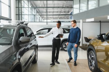 Erkek müşterinin portresi galeride profesyonel araba satıcısıyla konuşuyor. Yeni otomobil seçimi ve satın alma kavramı.