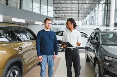 Bir araba galerisinde danışman, müşteriye yeni bir araba seçmesinde yardımcı olur..