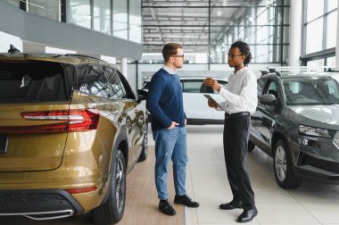 Bir araba galerisinde danışman, müşteriye yeni bir araba seçmesinde yardımcı olur..