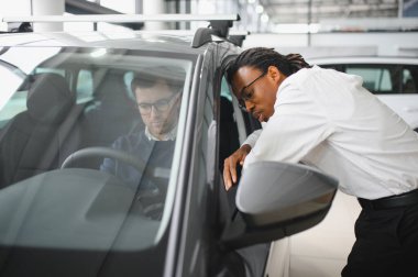 Bir araba galerisinde danışman, müşteriye yeni bir araba seçmesinde yardımcı olur..