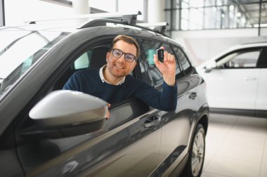 Genç adam yeni bir araç içinde araba Bayilik seçmektir.