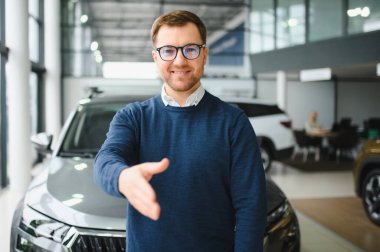 Genç adam yeni bir araç içinde araba Bayilik seçmektir.