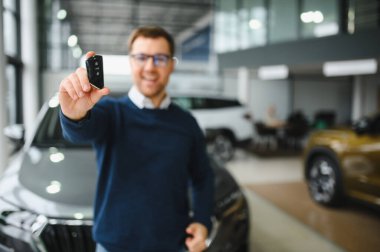 Genç adam yeni bir araç içinde araba Bayilik seçmektir.