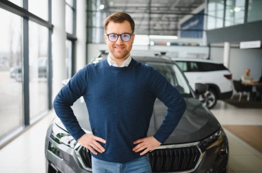 Genç adam yeni bir araç içinde araba Bayilik seçmektir.