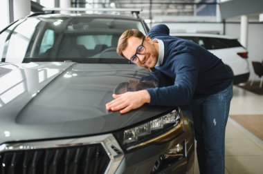 Genç adam yeni bir araç içinde araba Bayilik seçmektir.